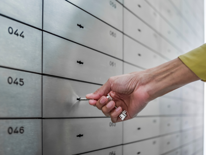 A row of safe deposit boxes with someone inserting a key.