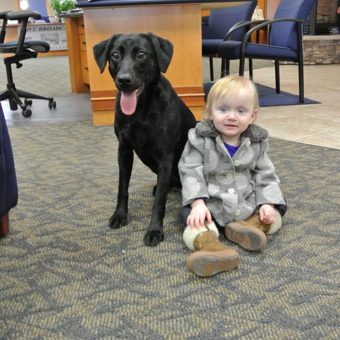 A dog sitting next to a baby